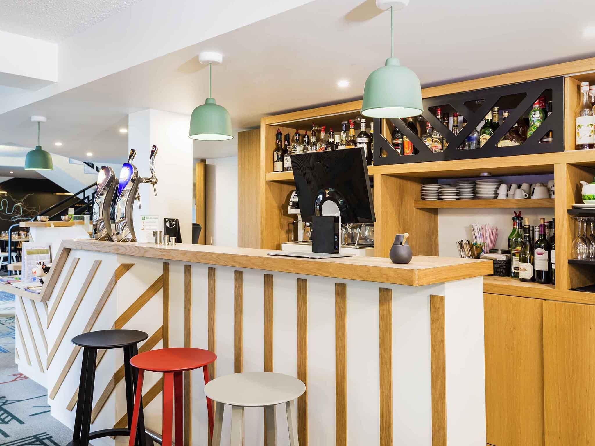 Eine Bar mit Holzböden, Hockern und Pendelleuchten.