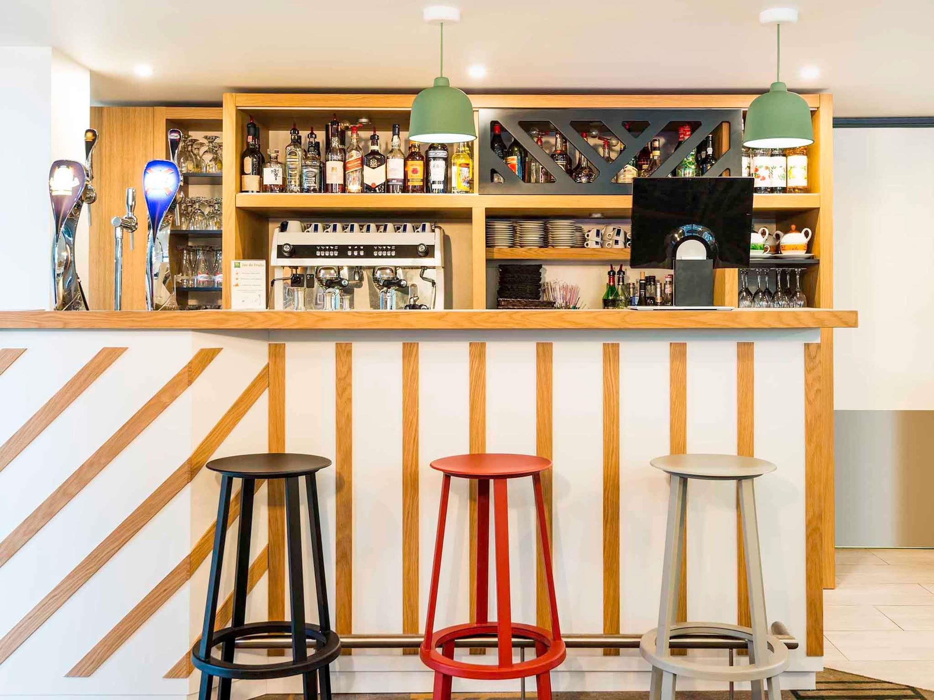 A bar area with shelves of bottles, a coffee machine, and three stools.