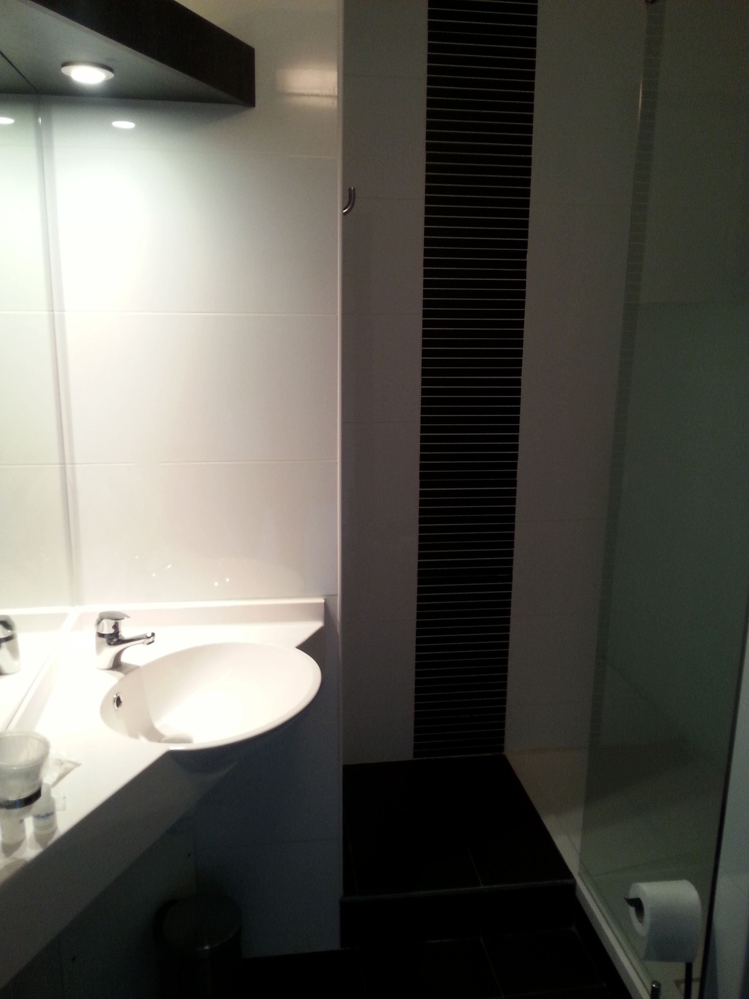 A modern bathroom with a white sink, mirror, and black tiled floor.