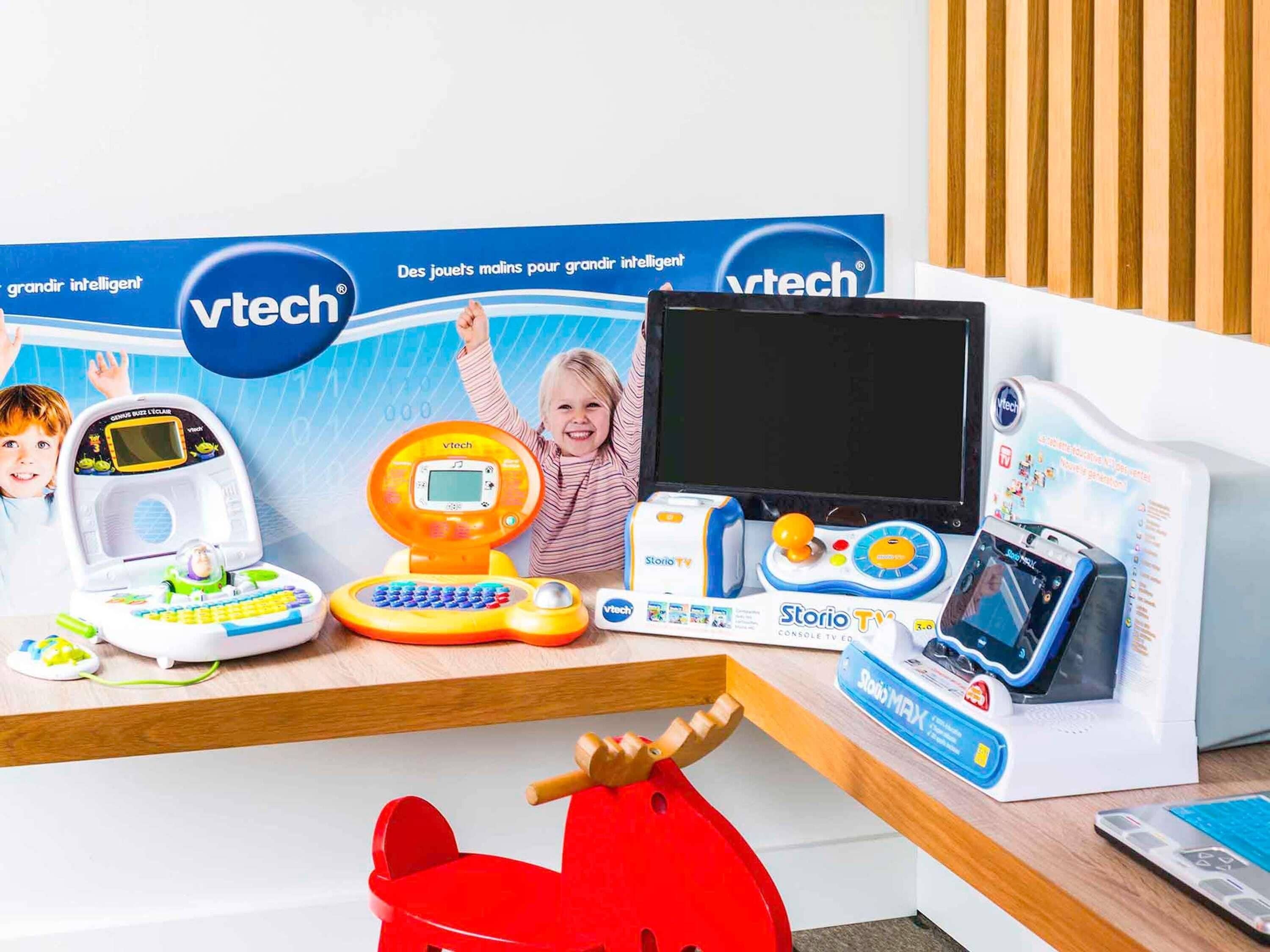 Zona de juegos infantiles con juguetes educativos y un mueble para televisión.