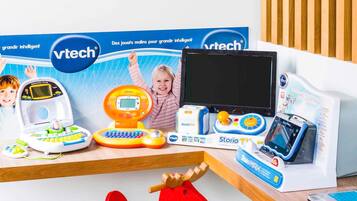 Zona de juegos infantiles con juguetes educativos y un mueble para televisión.