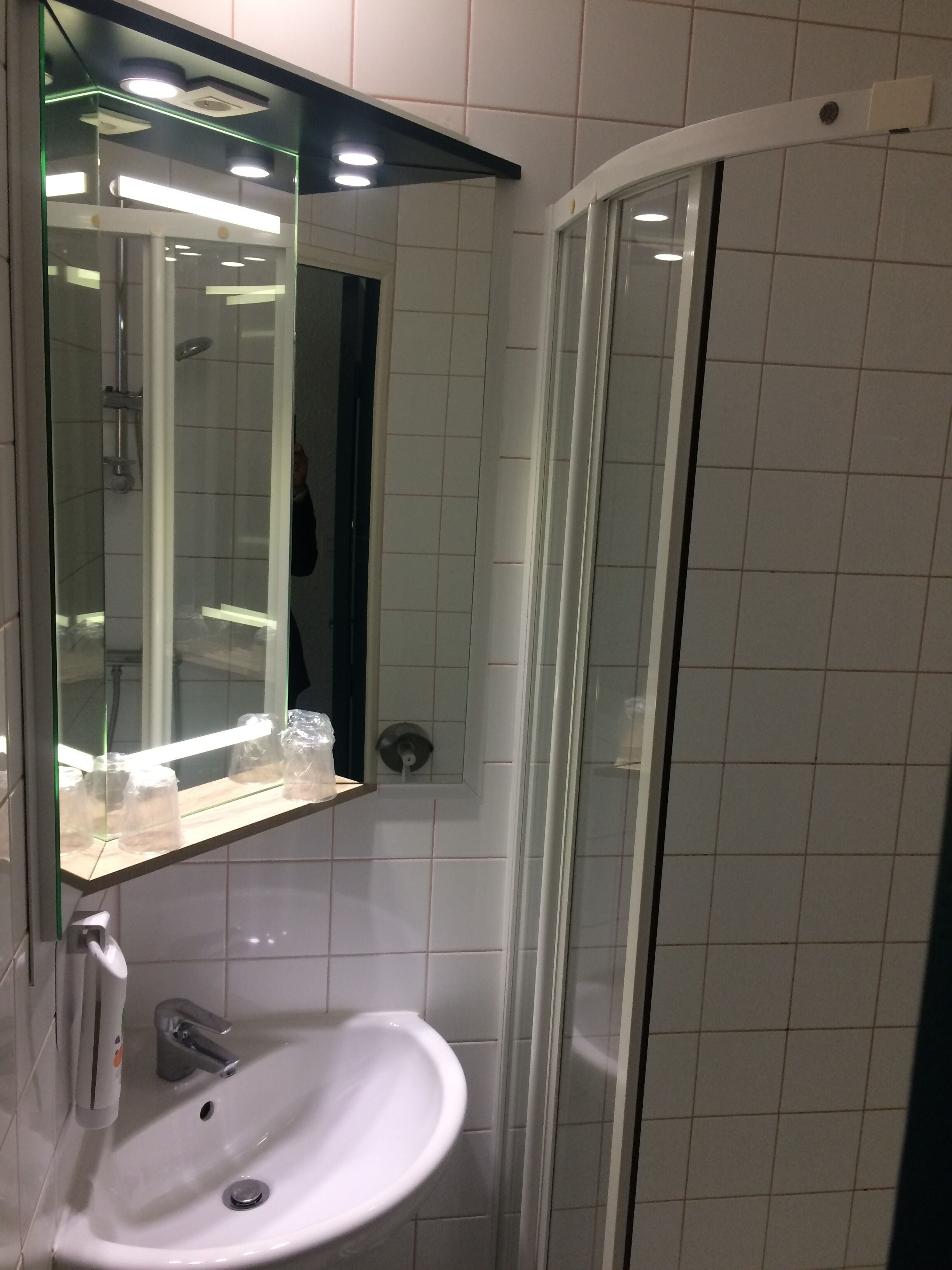 A bathroom with a glass-enclosed shower, a white sink, and a mirror above the sink.