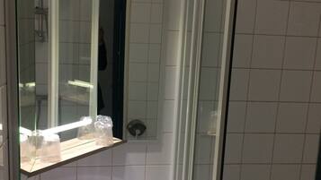 A bathroom with a glass-enclosed shower, a white sink, and a mirror above the sink.