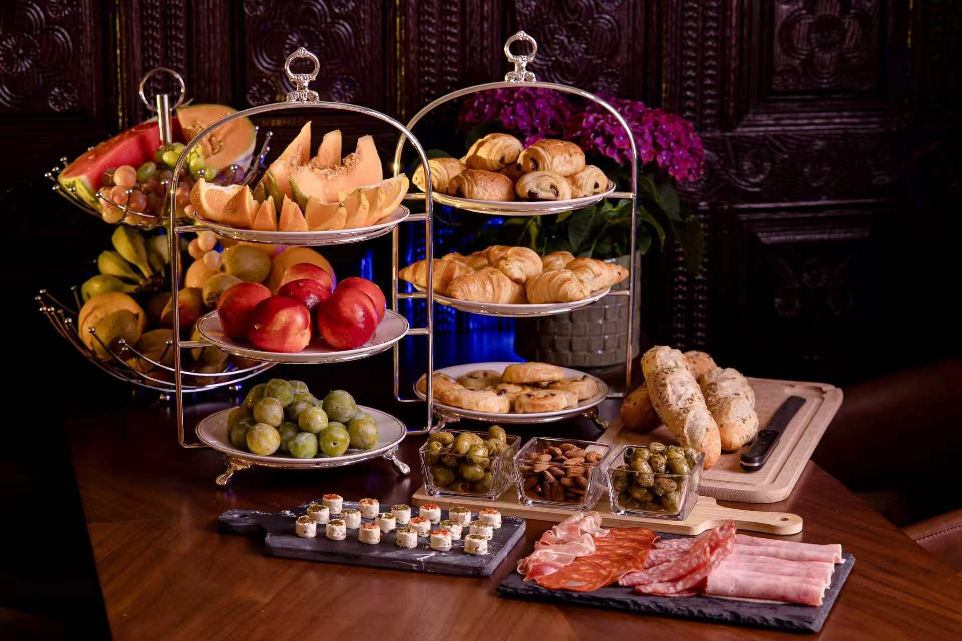 Un buffet con diversi cibi, tra cui frutta, pasticcini e carni.