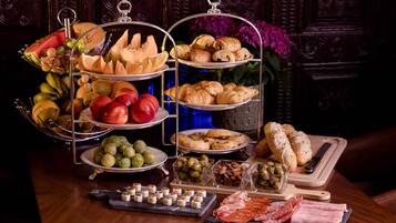 Un buffet con diversi cibi, tra cui frutta, pasticcini e carni.