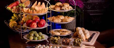 Un buffet proposant une variété de plats, notamment des fruits, des pâtisseries et des viandes.