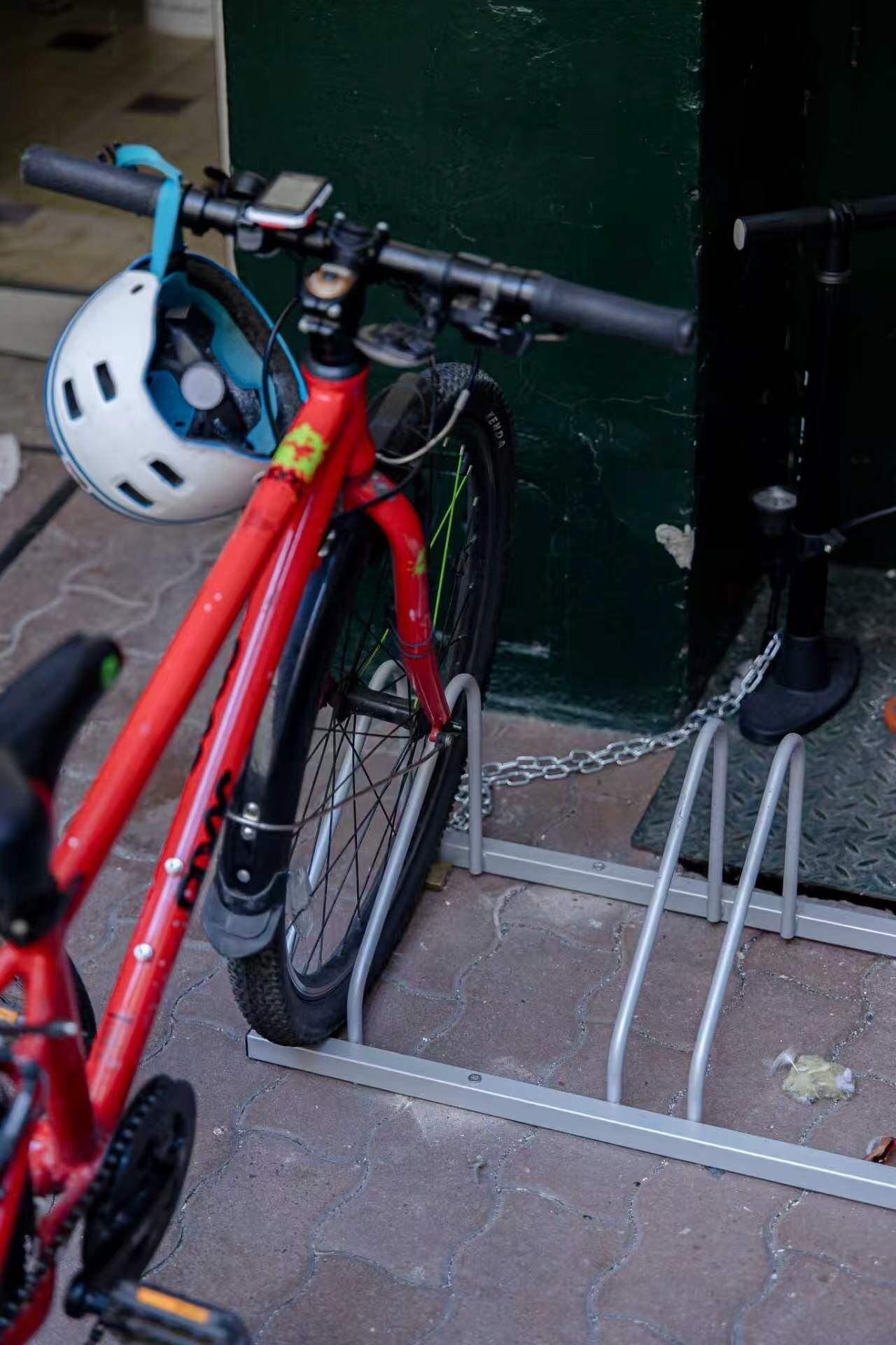 Ein rotes Fahrrad, das an einem Metallgestell vor einem Gebäude befestigt ist.