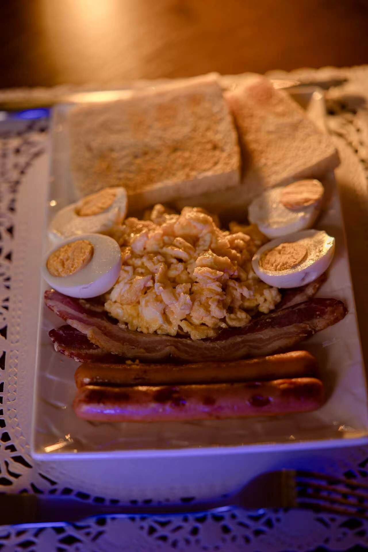 A plate with scrambled eggs, bacon, toast, and hard-boiled eggs.