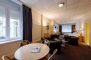 A hotel room with a dining area, a bed, and a bathroom. - Hôtel Metropol (Calais)