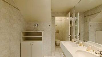 A modern bathroom with a vanity, a large mirror, a toilet, and a shower area.