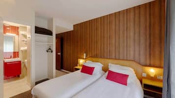 A hotel room with two beds, a red bathroom, and wooden paneling on the wall.