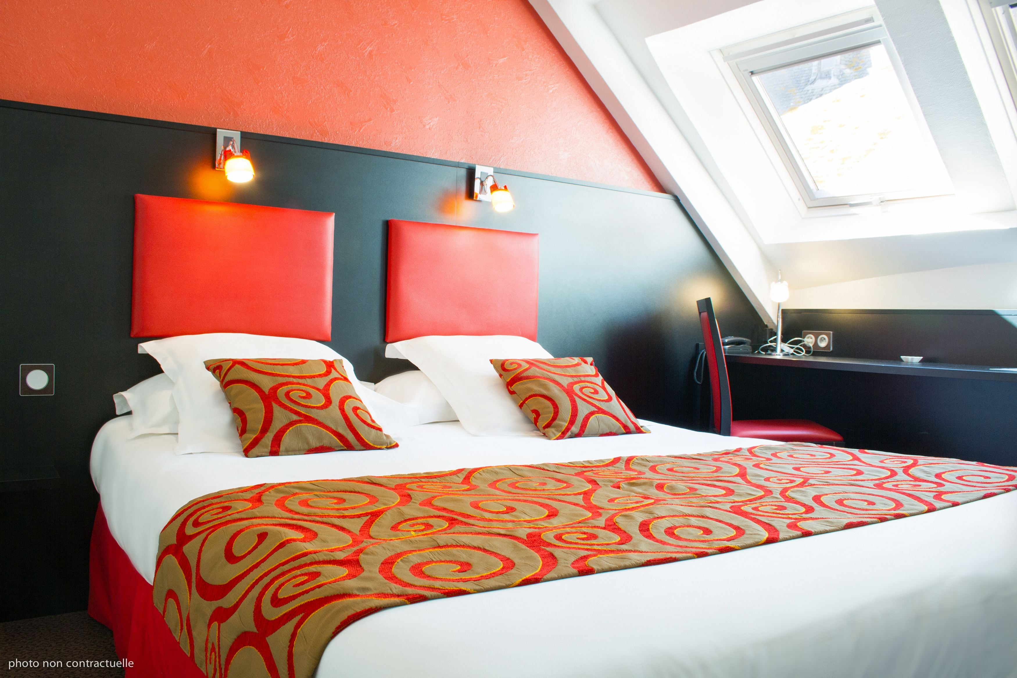 Une chambre d’hôtel avec un grand lit, une literie rouge et blanche, et un design moderne.