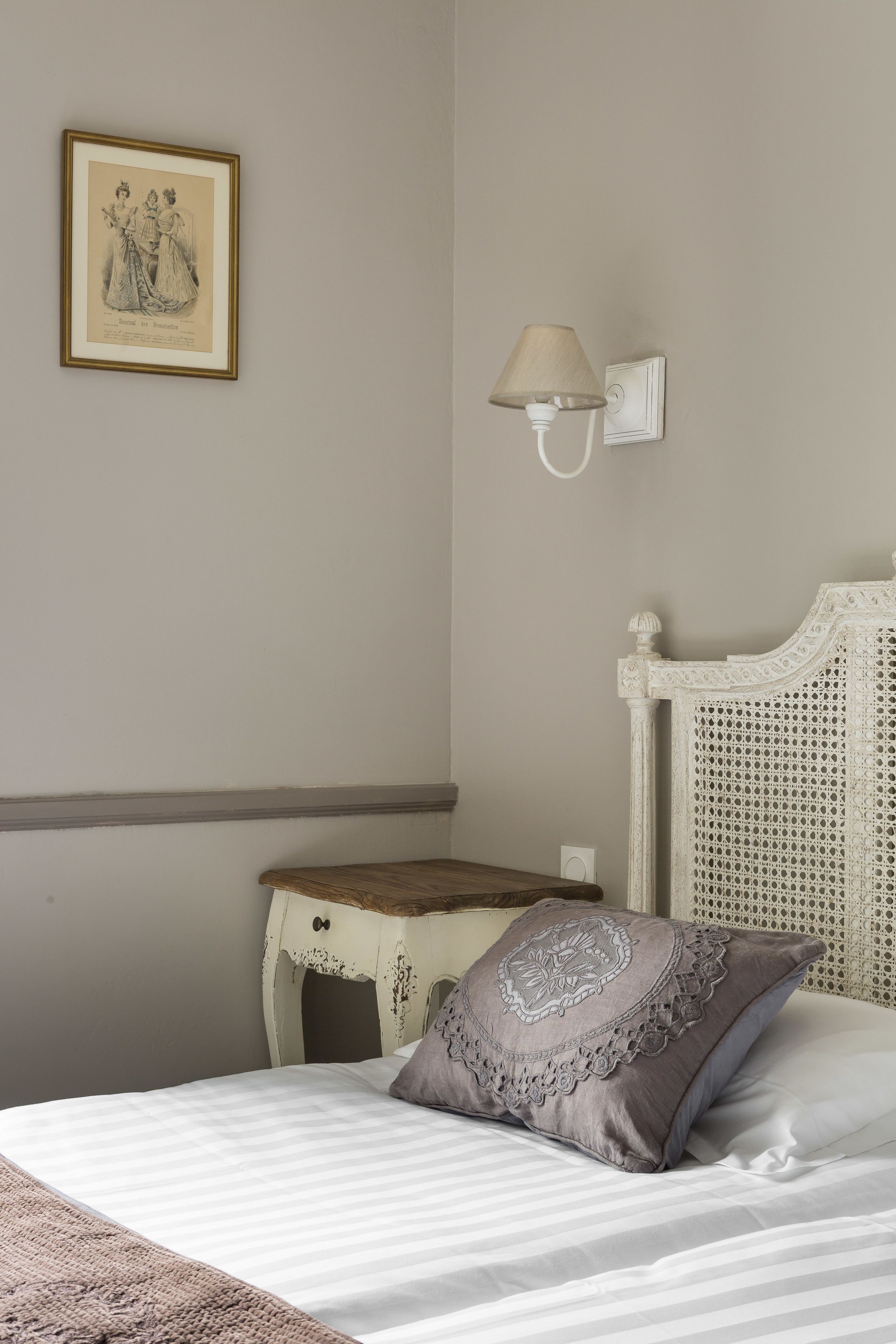 A bedroom with a bed, a bedside table, a lamp, and a framed picture on the wall.