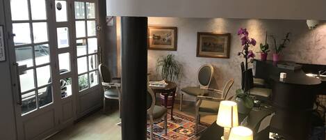 A spacious living area with a large window, a dining table, chairs, a rug, and a sofa.
