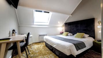 A bedroom with a bed, a desk, and a chair. There is a skylight above the bed.
