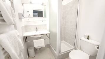 A modern bathroom with a glass-enclosed shower, a white sink, and a toilet.