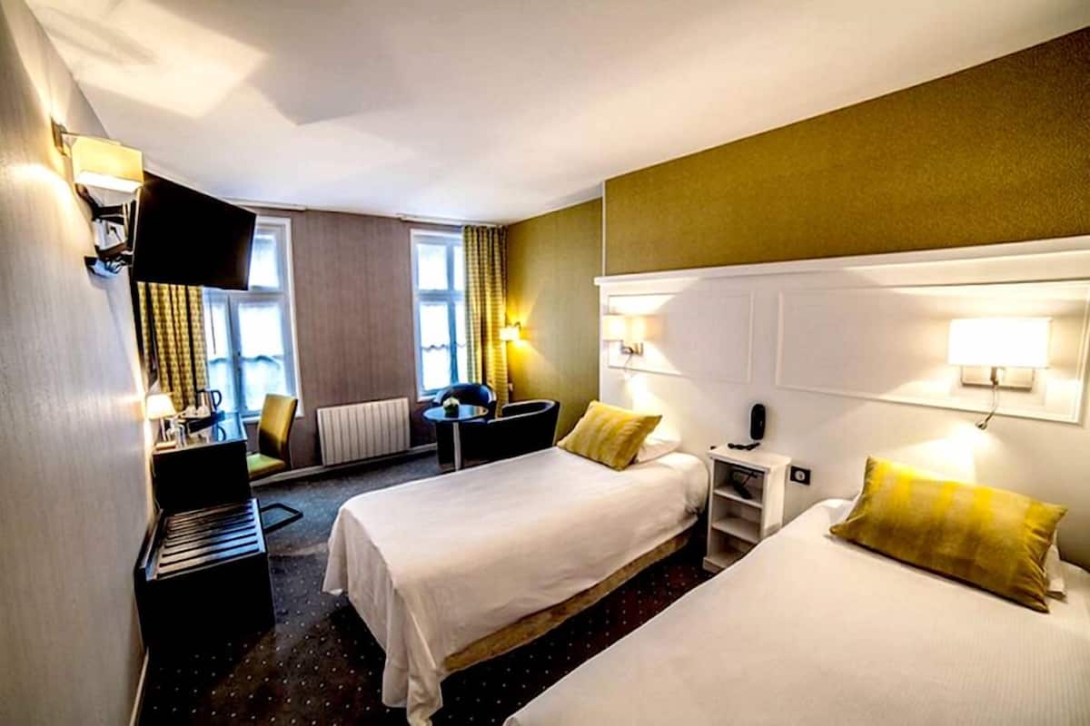 A hotel room with two beds, a desk, a chair, a piano, and a TV.