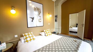 A hotel room with a large bed, two bedside tables, a wall-mounted artwork, and a door leading to another room.