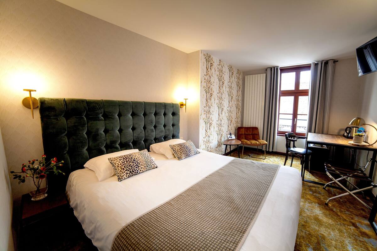 A hotel room with a large bed, a desk, and a chair.