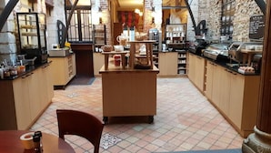 A café with a rustic brick wall, a central wooden counter, and a tiled floor. - Les Hauts de Montreuil (Montreuil-sur-Mer)