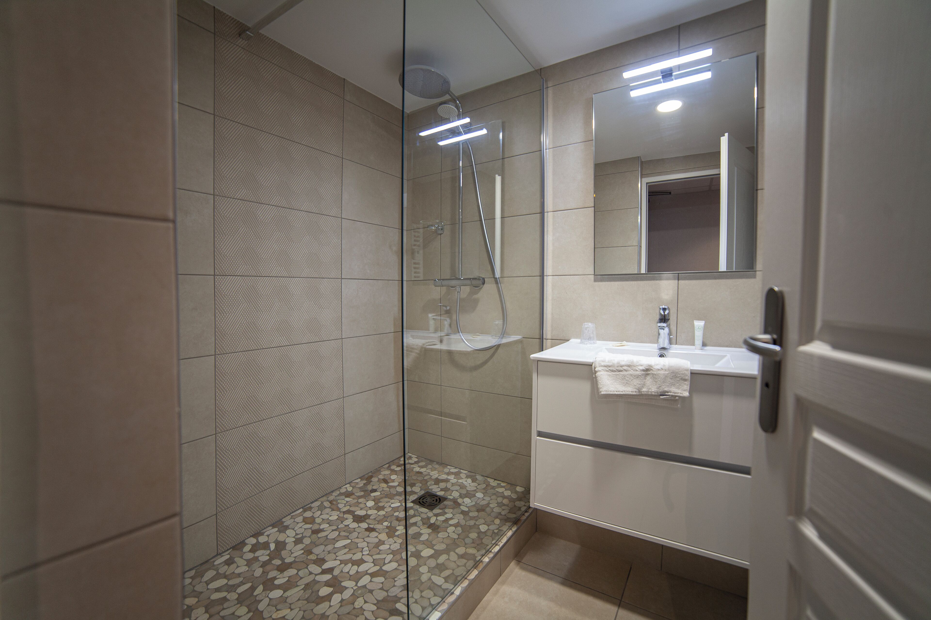 A modern bathroom with a glass-enclosed shower, a white sink, and a mirror above the vanity.
