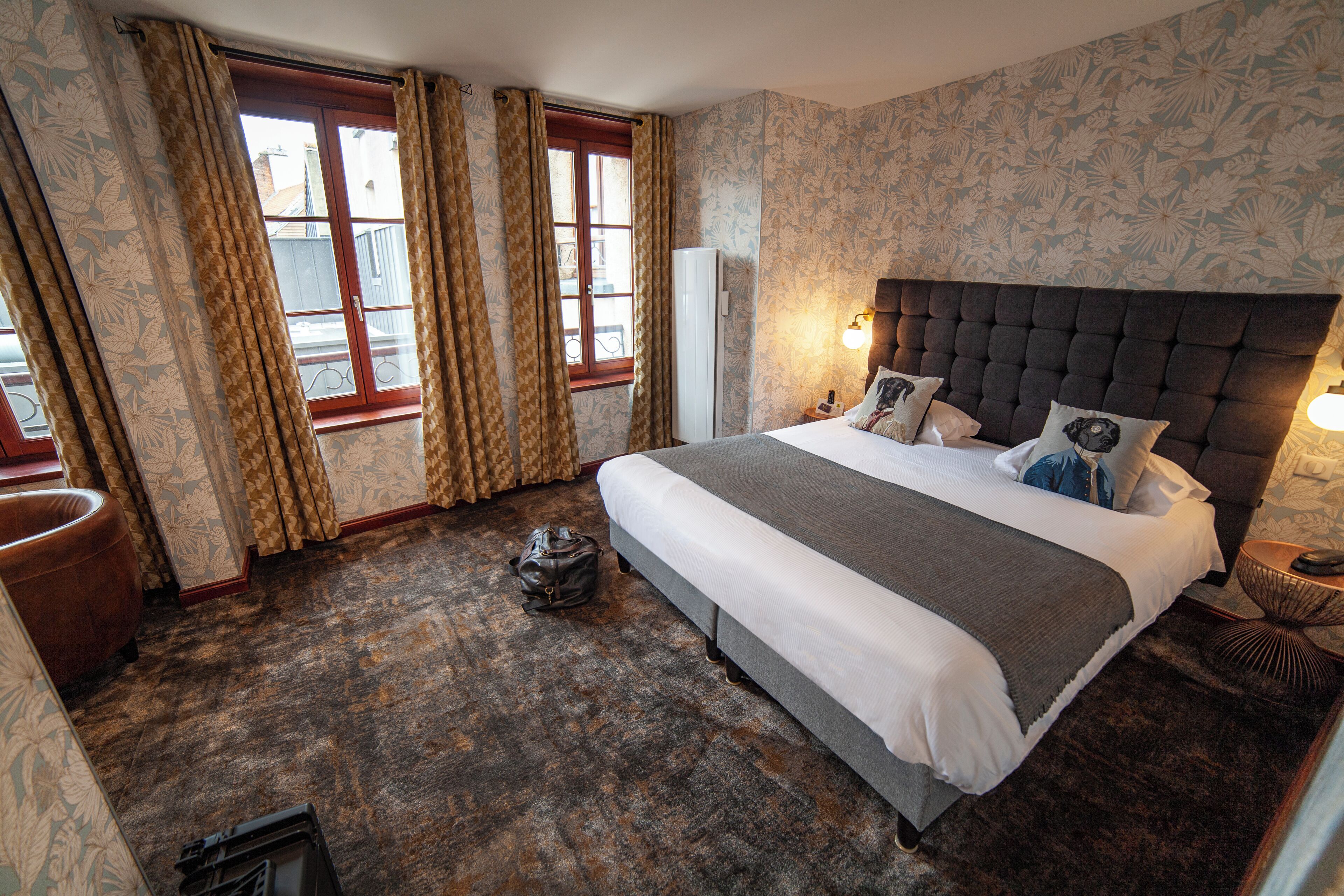 Une chambre avec un grand lit, une armoire, une table de chevet et une fenêtre avec des rideaux.