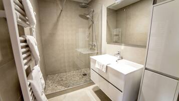 A modern bathroom with a glass-enclosed shower, a white sink, and a mirror above the vanity.