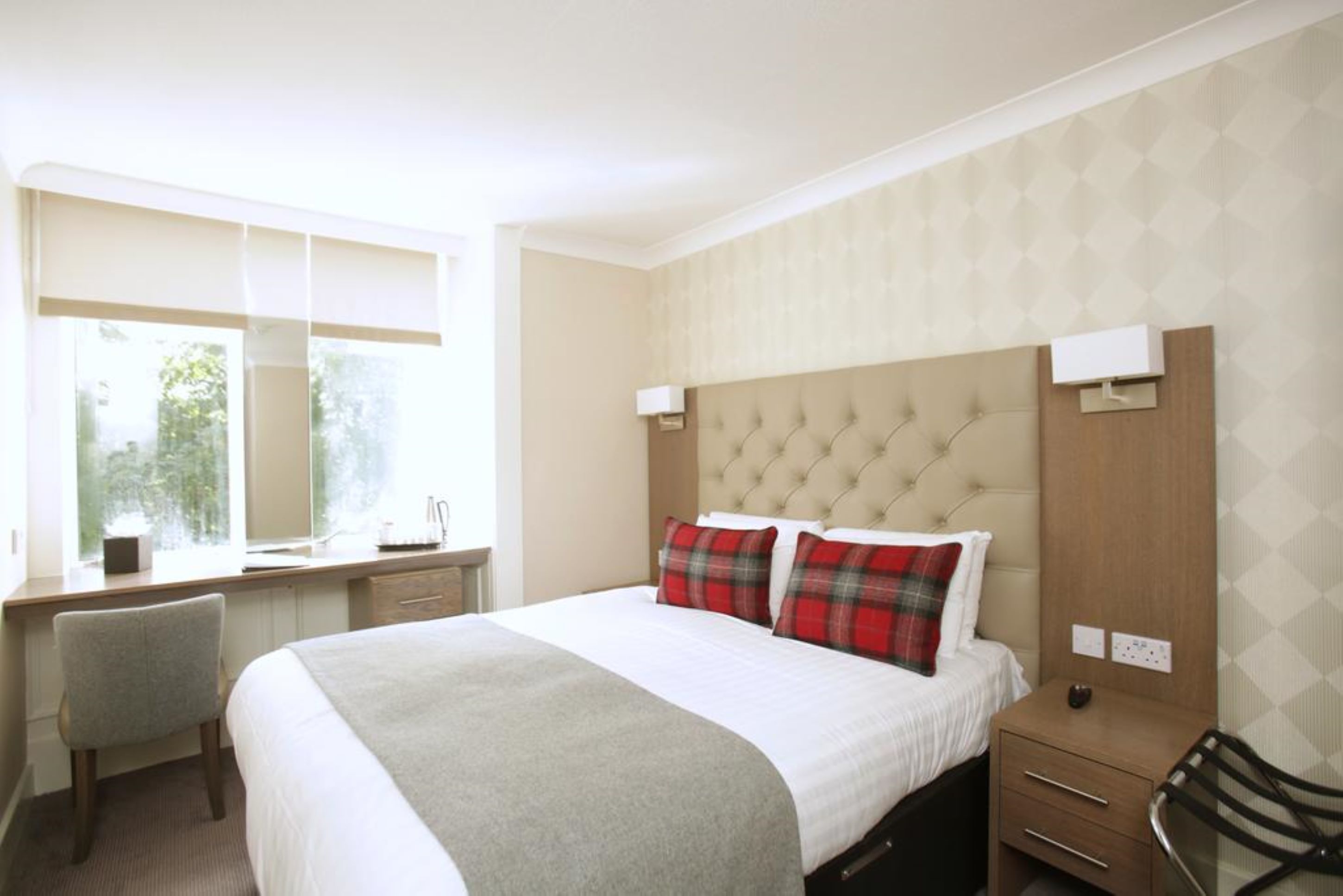 A hotel room with a large bed, a desk, and a chair.
