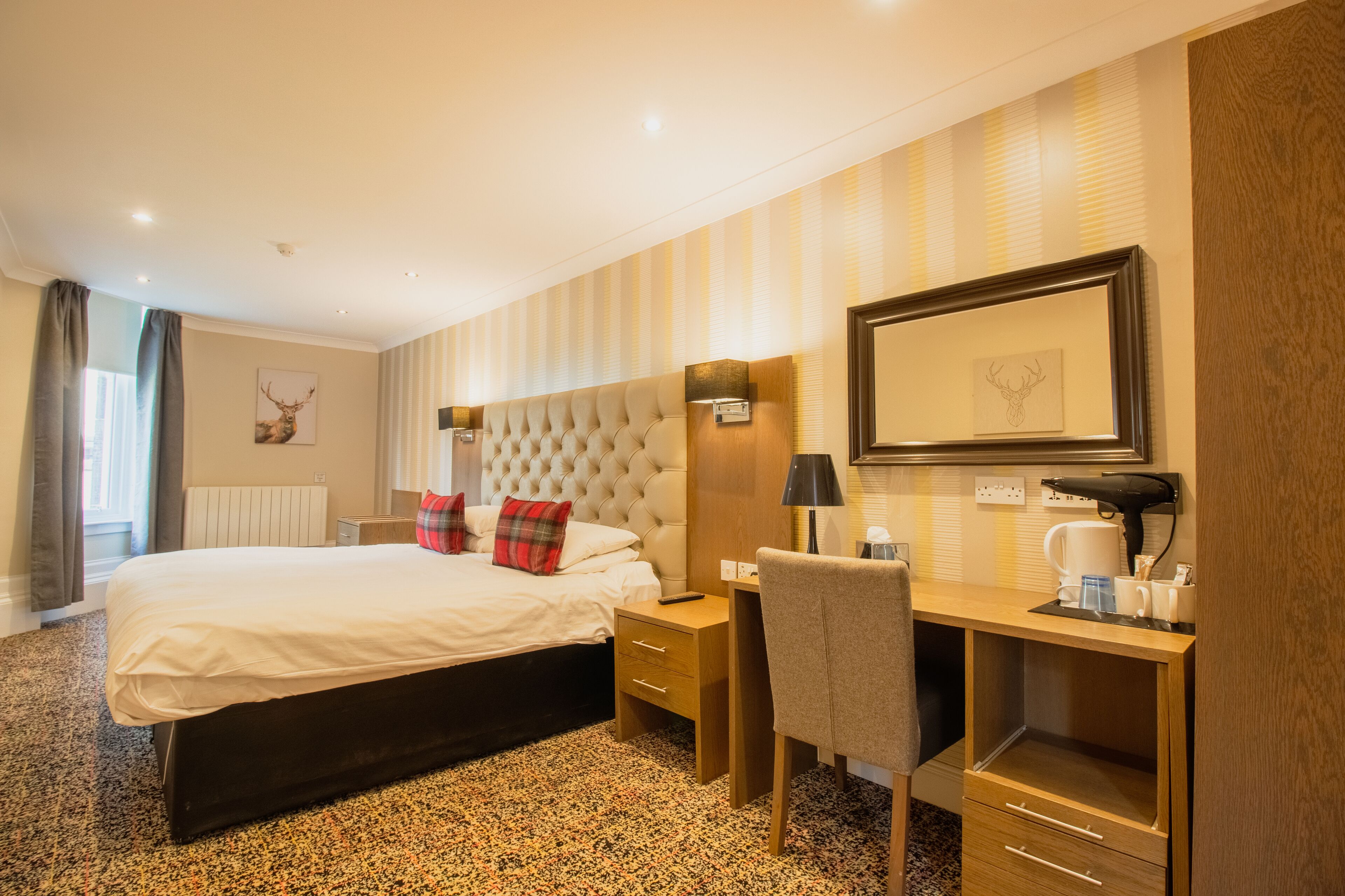Une chambre d’hôtel avec un grand lit, un bureau avec une chaise, un miroir et un radiateur.