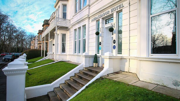 A row of townhouses with a well-maintained lawn and a staircase leading to the entrance. - Ambassador Hotel (Glasgow)