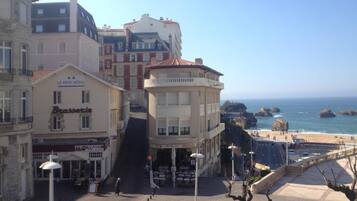 A hotel with a terrace overlooking a beach, featuring a 'Le Petit Hotel' sign, a 'Brasserie' restaurant, and a 'Pub & Grill' establishment.