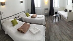 A hotel room with two single beds, a small table, a chair, and a TV. - Le Petit Hôtel (Biarritz)