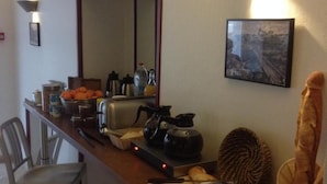 A kitchen counter with a coffee maker, toaster, and a bowl of oranges. - Le Petit Hôtel (Biarritz)