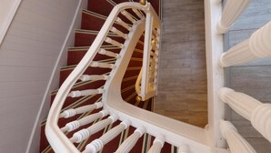 A spiral staircase with white balusters and a red carpeted floor. - Le Petit Hôtel (Biarritz)