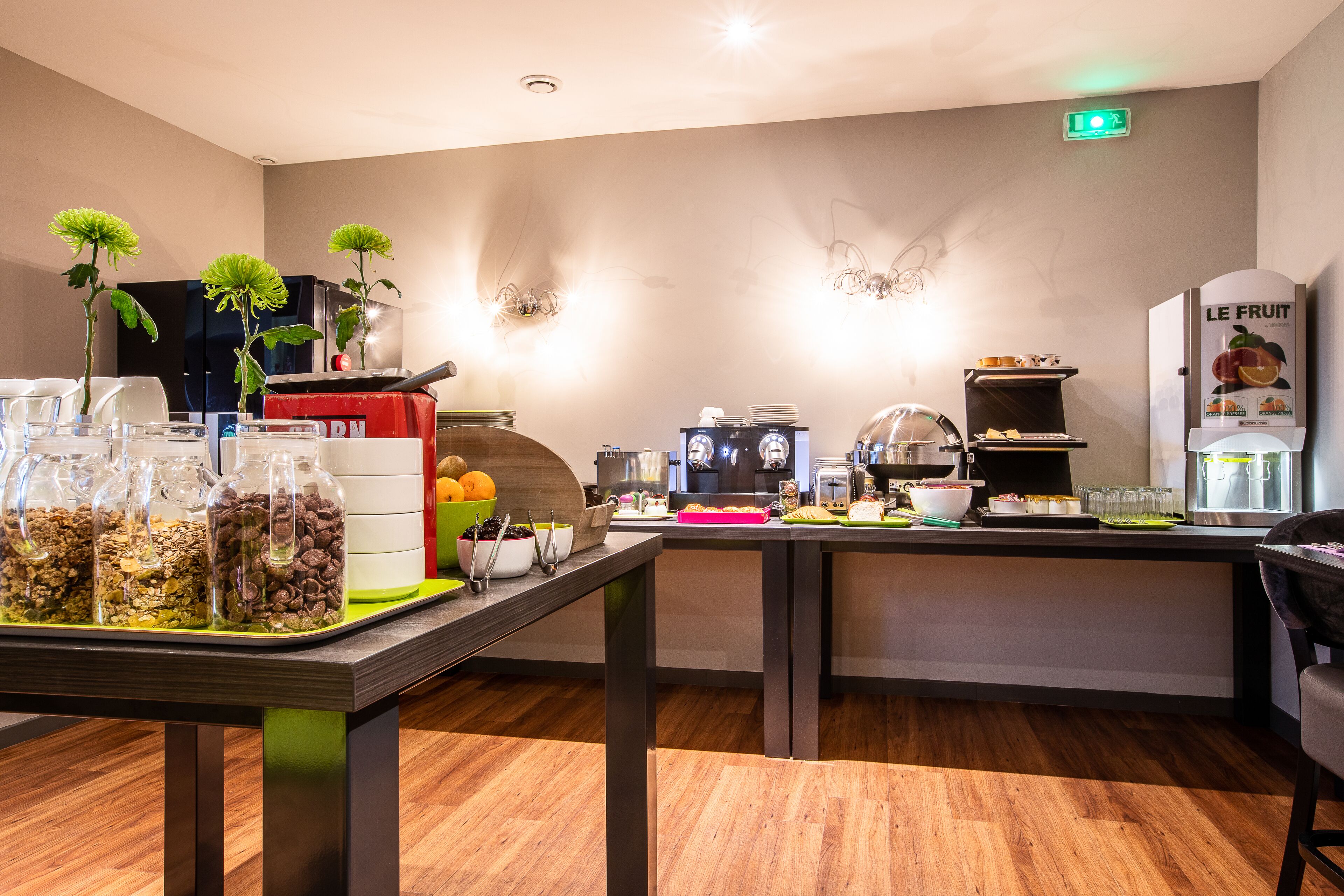 A modern kitchen area with a buffet setup, including glass jars of food, a coffee machine, and a fruit dispenser.