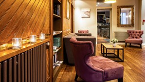 A modern living room with a wooden panel wall, a purple armchair, a sofa, and a dining area with a table and chairs. - Hôtel des Dunes (La Baule-Escoublac)