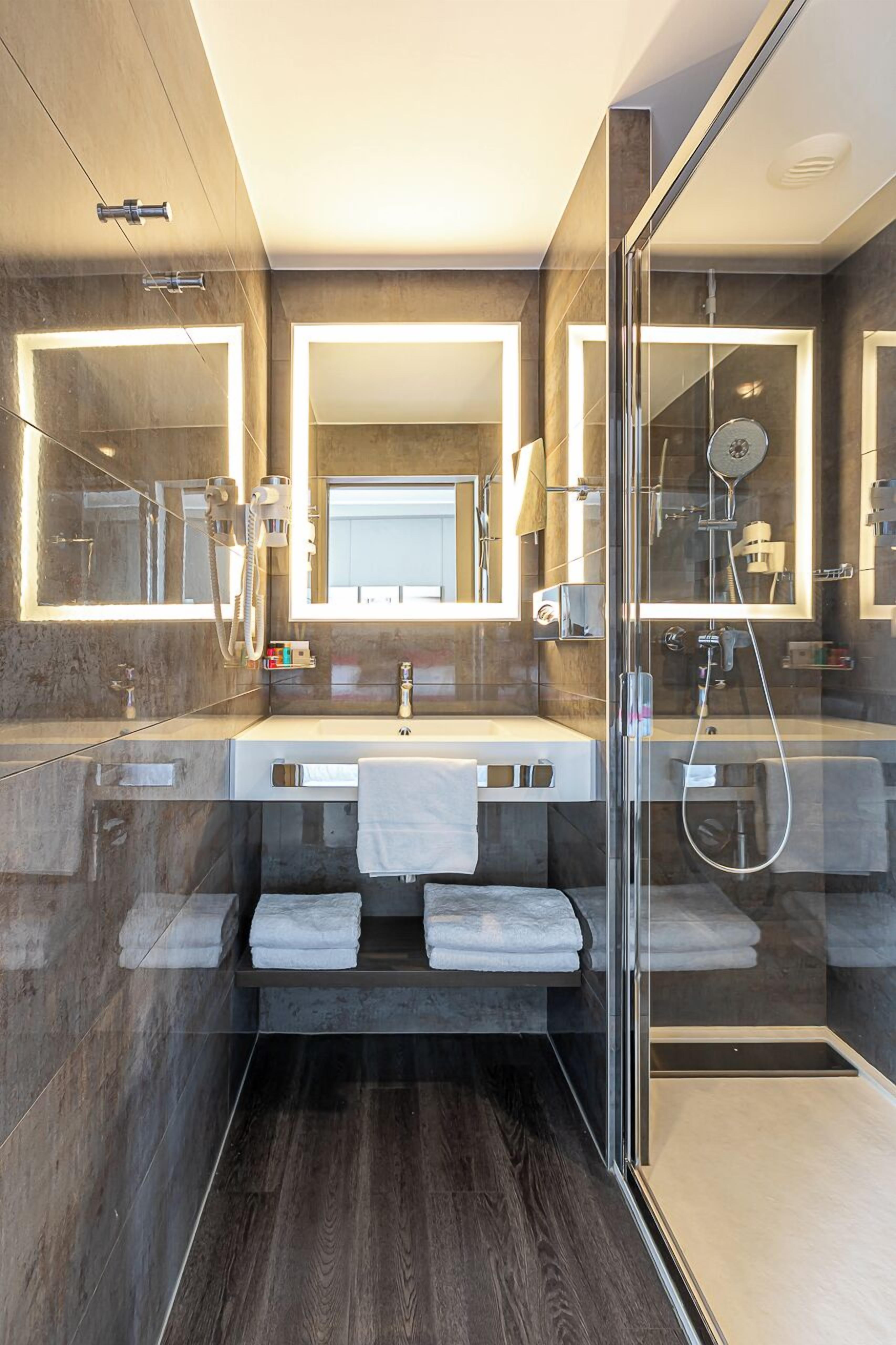 A modern bathroom with a glass-enclosed shower, a vanity with a mirror, and a towel rack.