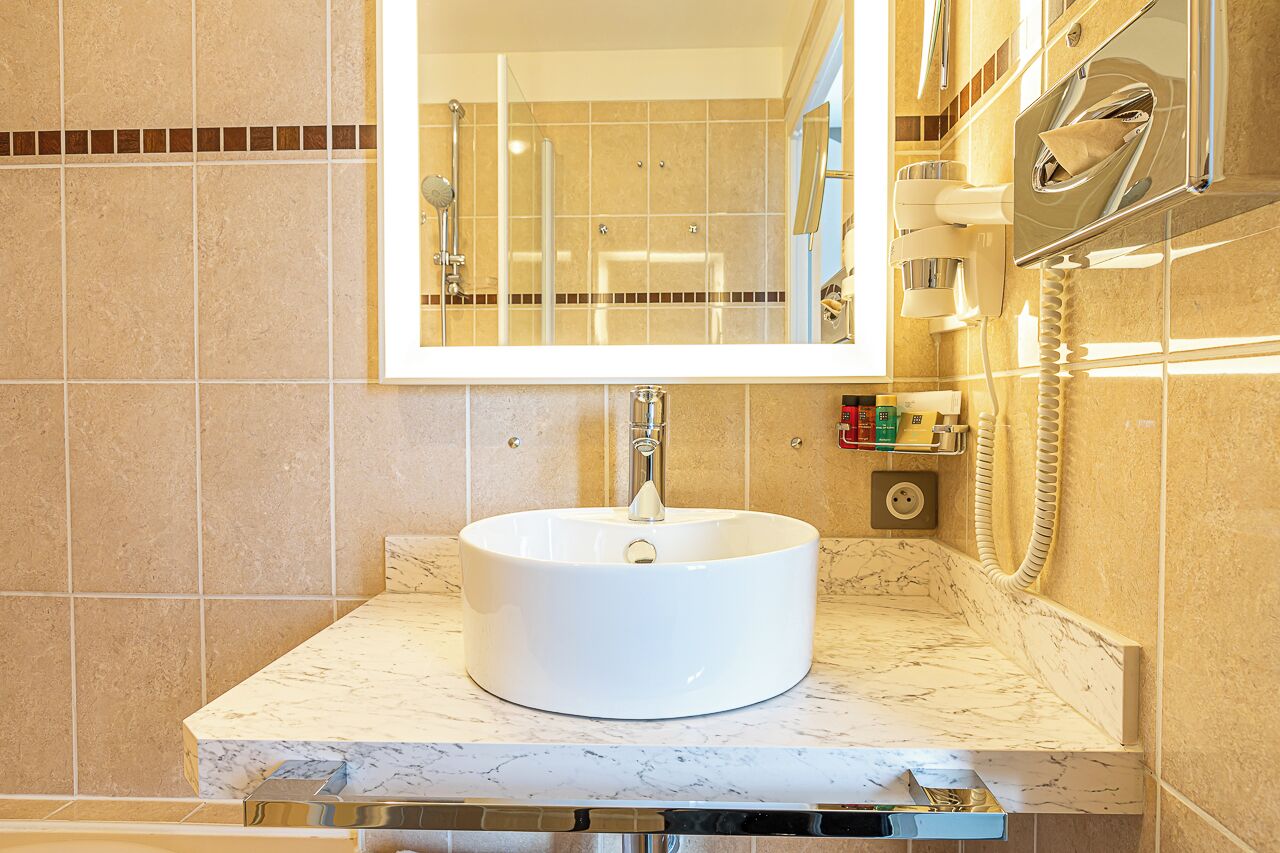 Un baño con un lavamanos blanco, un espejo y una ducha.