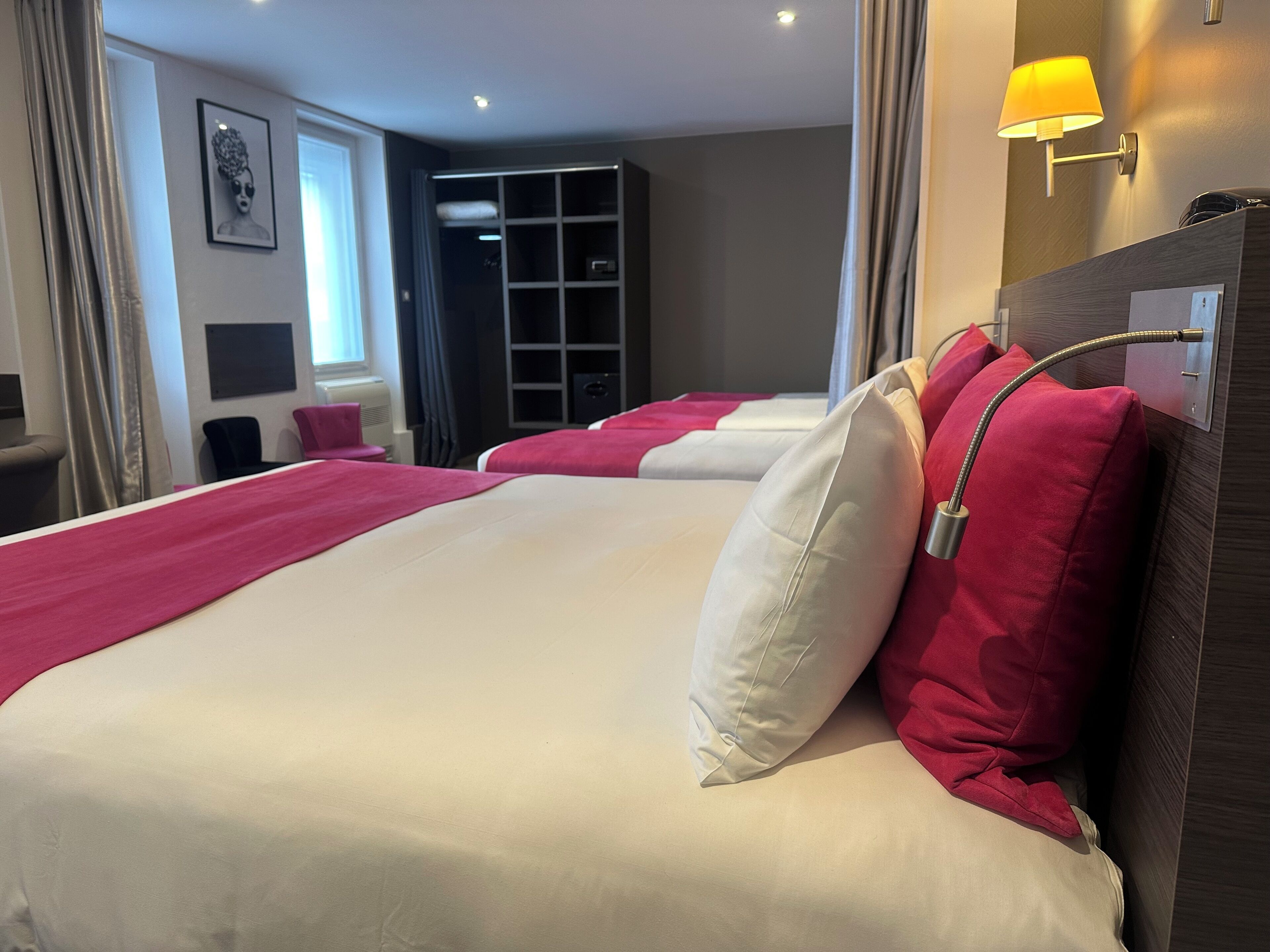 Habitación de hotel con dos camas, un armario, un escritorio y una ventana con cortinas.