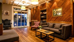 A modern lobby with a wooden wall, a sofa, a chair, and a coffee table. - Hôtel des Dunes (La Baule-Escoublac)