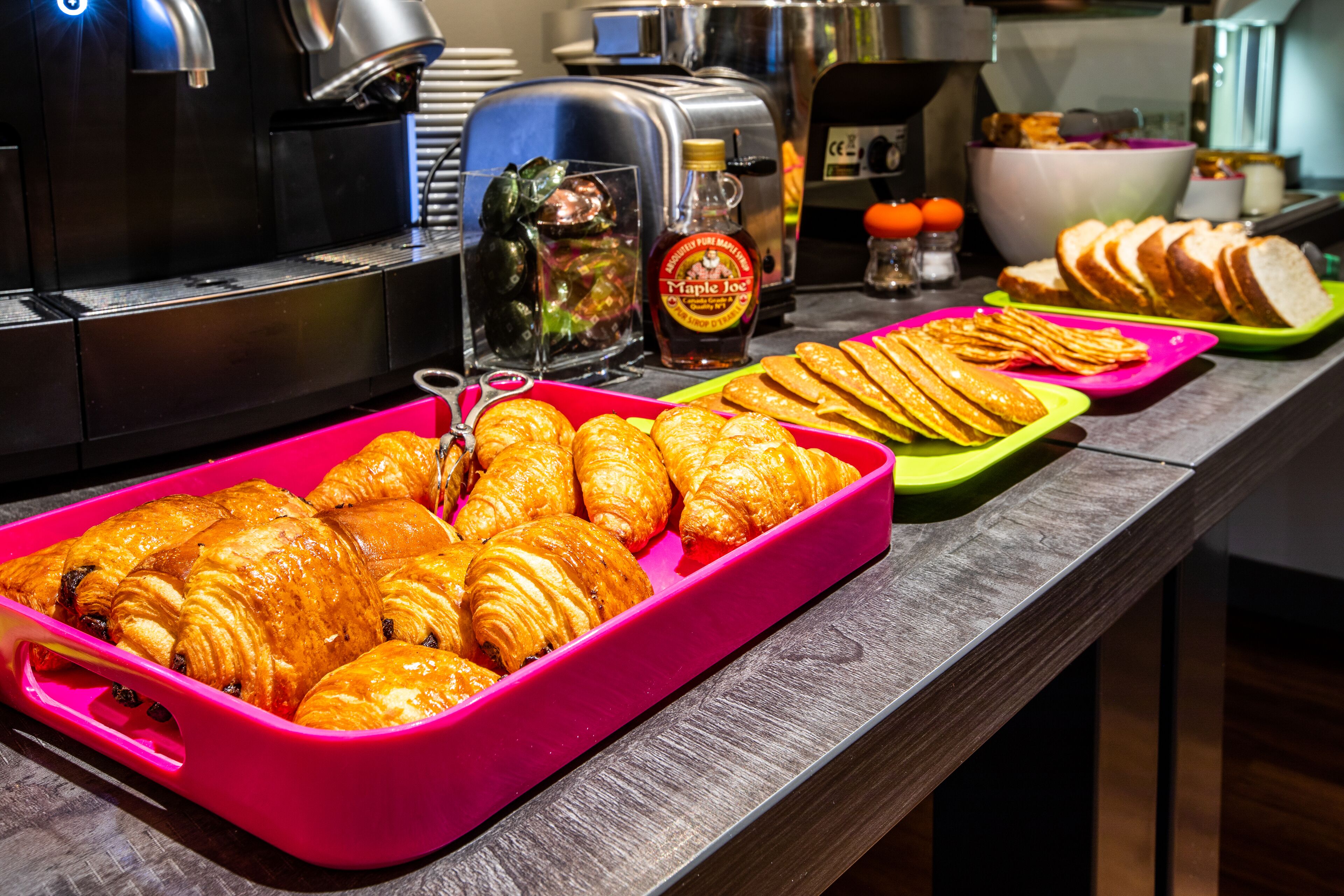 A breakfast buffet with pastries, bread, and condiments.