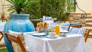 An outdoor dining area with a table set for breakfast, including bread, eggs, and juice. - La Maison d'été (Salon-de-Provence)