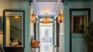 A hotel lobby with a checkered floor, a seating area with chairs, and a large mirror on the wall. - La Maison d'été (Salon-de-Provence)