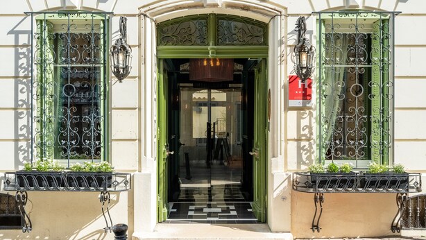 A building entrance with ornate iron gates, a green door, and a small balcony with plants. - La Maison d'été (Salon-de-Provence)