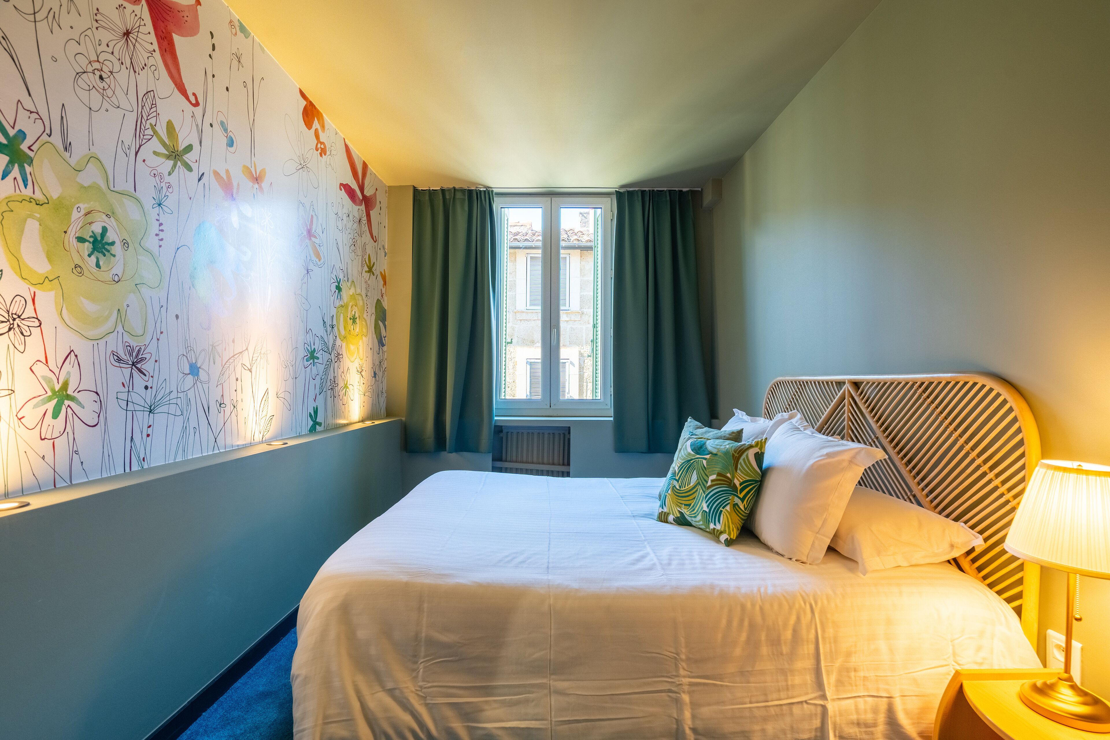 A neatly made bed with white linens, a headboard with a geometric pattern, and a bedside lamp.