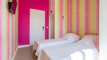 A room with two beds, a door, and a wall with a striped pattern.