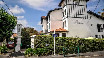 Ein Hotel namens "Les Coëlands" mit traditioneller Architektur, einem verschlossenen Eingang und blauem Himmel.