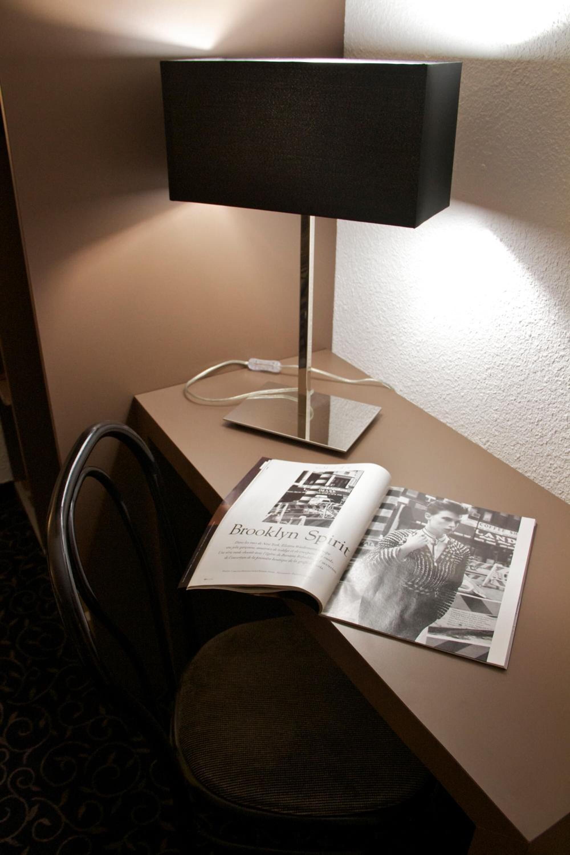 A desk with a lamp, a chair, and a magazine open to a page titled "Brooklyn Spirit."