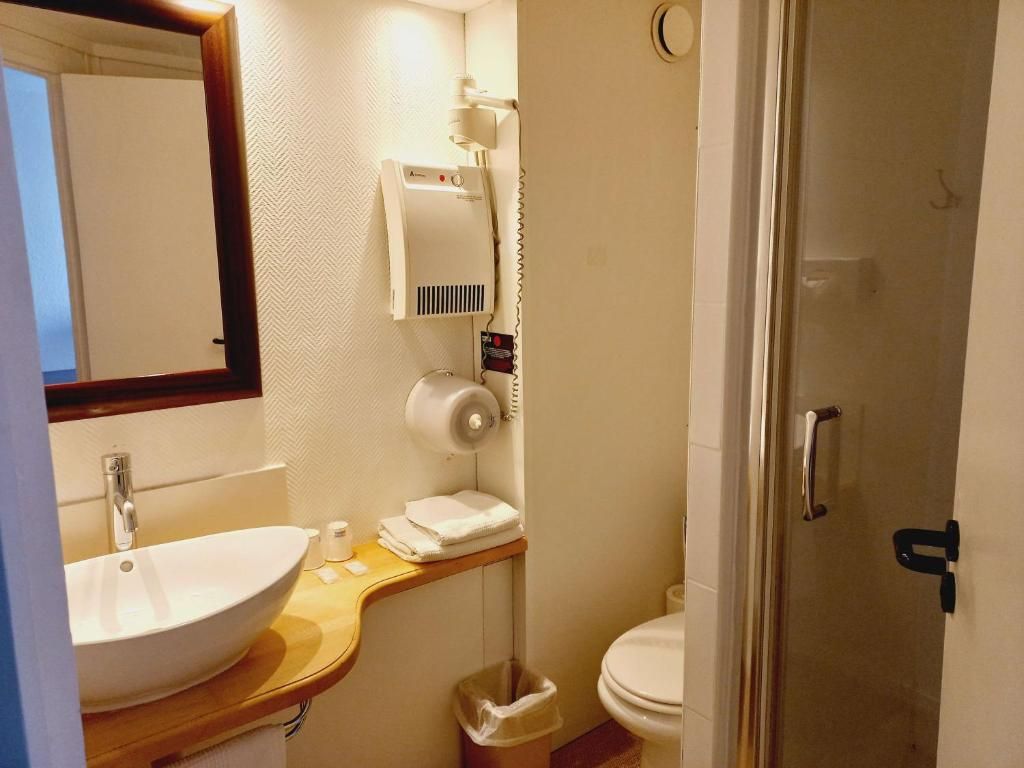 A bathroom with a sink, mirror, towel rack, and a hairdryer on the wall.