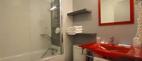 A bathroom with a glass shower enclosure, a white toilet, a red sink, and a mirror with a red frame.